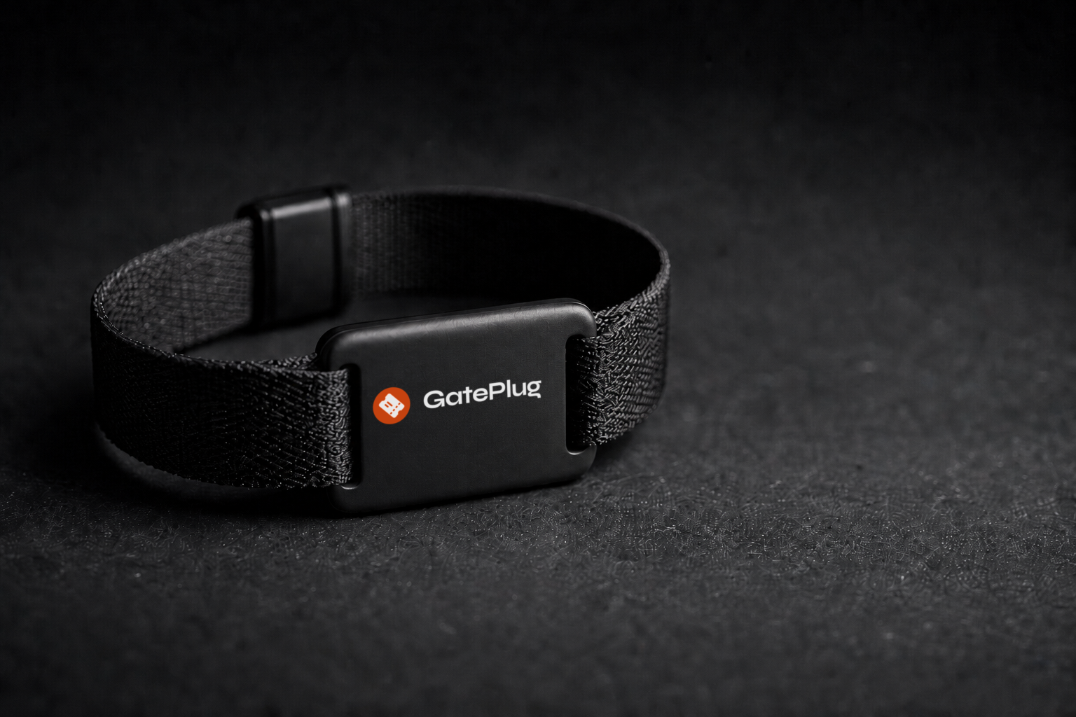 A black GatePlug cashless event wristband resting on a table